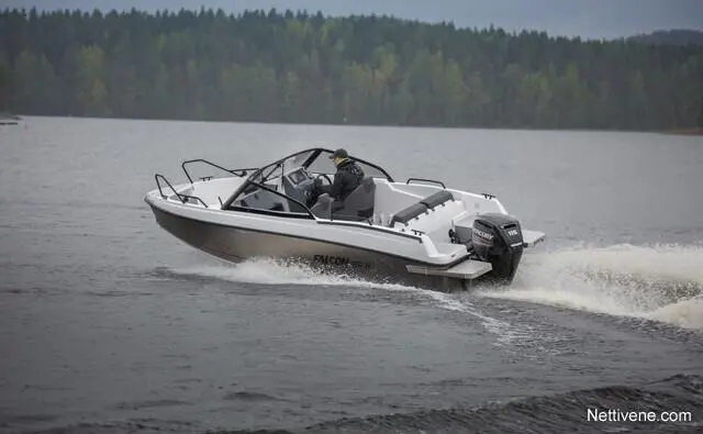 A sleek white Falcon boat with a driver accelerates on a lake, creating a wake against a backdrop of dense green forests.